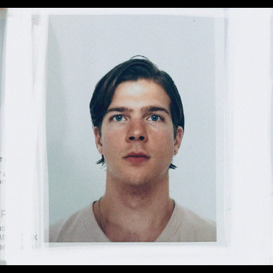 Man with brown ear-length hair faces camera